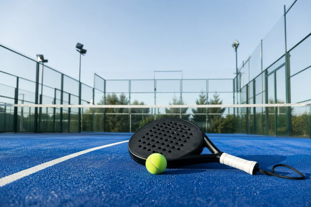 Dynamic action shot of a tennis player mid-serve on a professional blue hardcourt with bright sunlight and cinematic motion blur